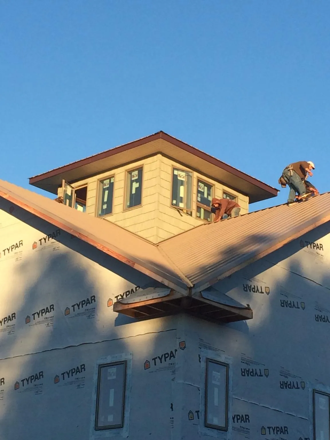 Roofers working around a rooftop cupola on a new metal roof at sunset — Roof Waterproofing in Courtland by Roofing Brothers